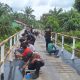 Warga bersama personel kepolisian bergotong royong mempercepat pembangunan jembatan di Kampung Buatan I, Kecamatan Koto Gasib, Kabupaten Siak, Minggu (1/2/2026).